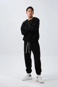 Man wearing a loose-fit black polar fleece jacket and matching trousers, a two-piece winter sports suit.