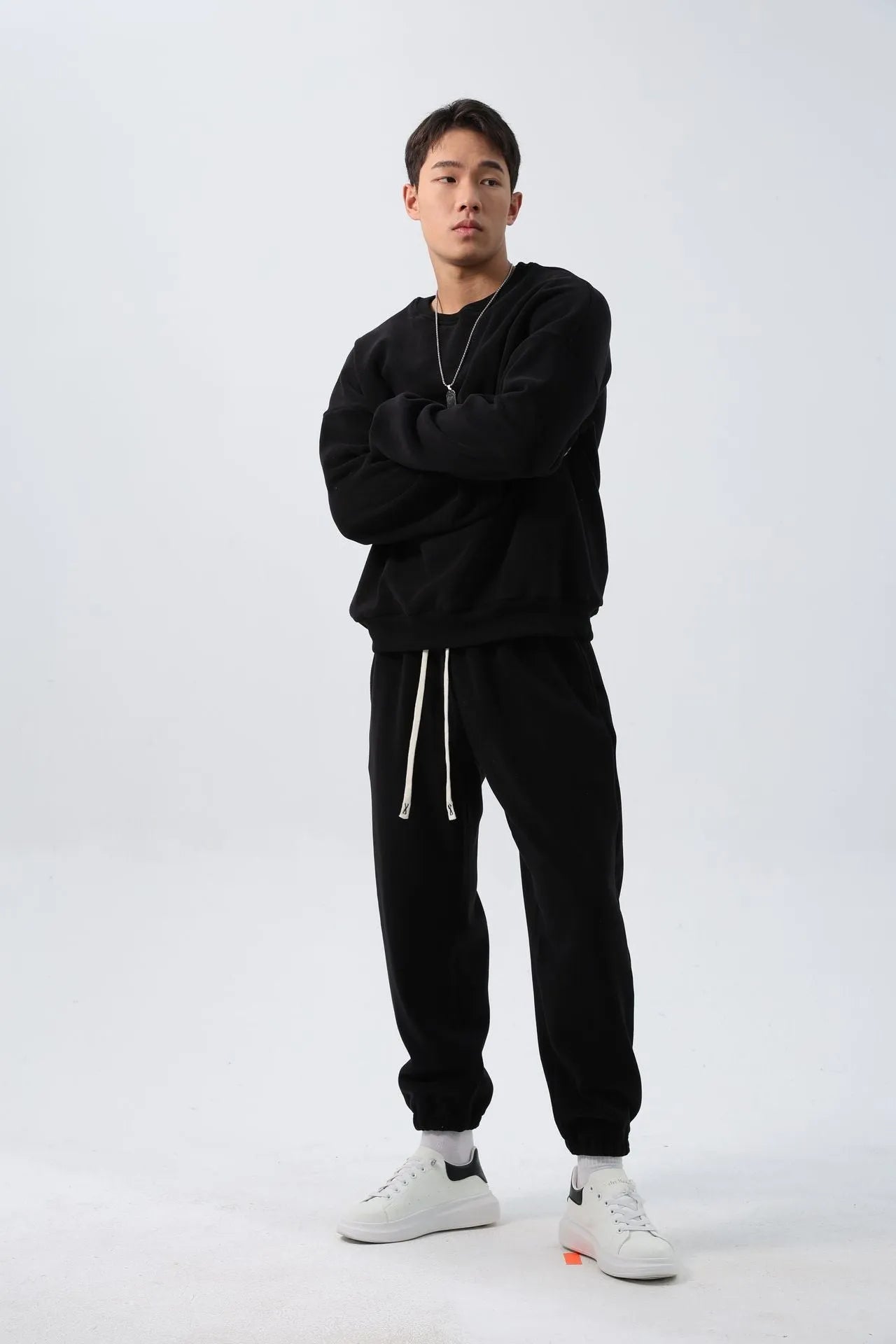 Man wearing a loose-fit black polar fleece jacket and matching trousers, a two-piece winter sports suit.
