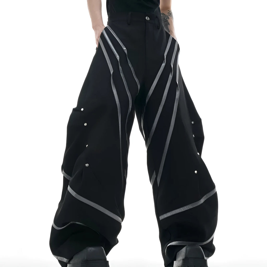 Men's black trousers with metal striped rivet details, pleated front, and a structured three-dimensional cut.