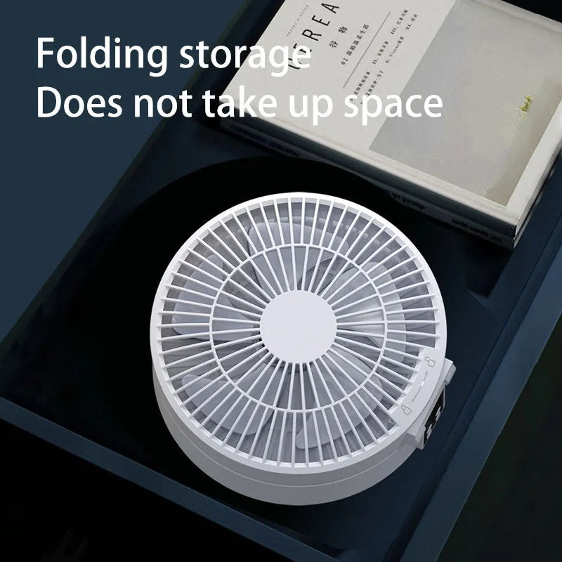 White portable folding fan with night light on a table, remote control beside it, showing its compact size.