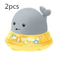 White and blue electric whale bath toy spraying water with lights on a base.