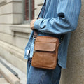 Men's brown genuine leather crossbody shoulder bag with visible stitching.