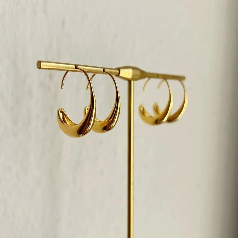 Gold electroplated alloy snake design drop earrings on a neutral background