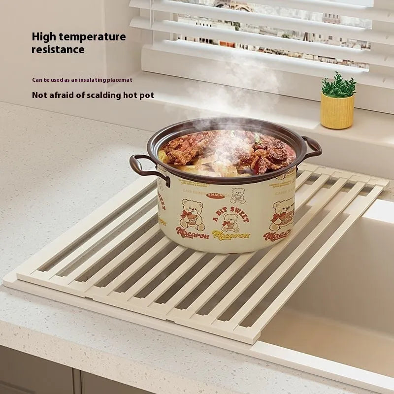 Milky white foldable stainless steel kitchen draining rack placed next to a sink.