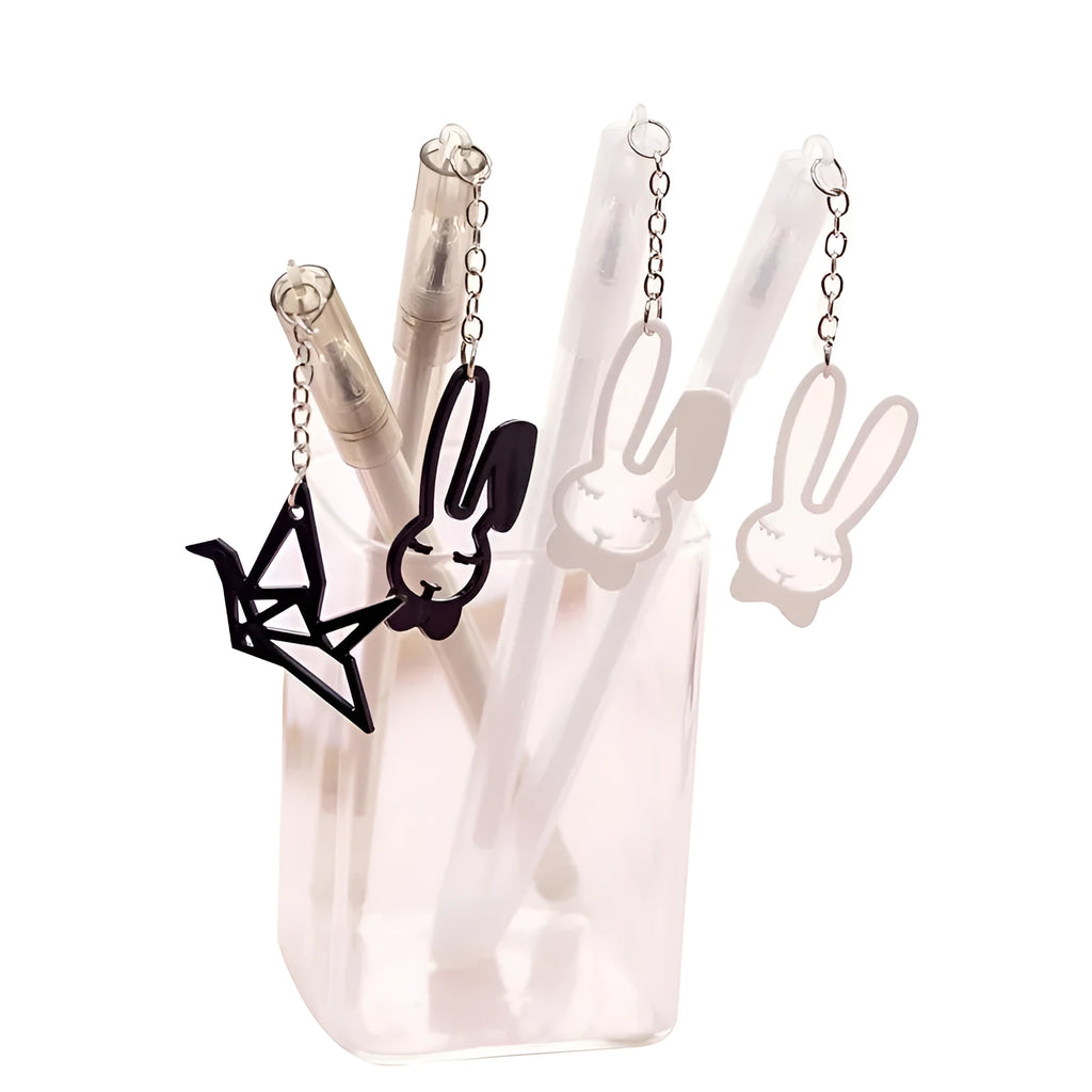 White gel pen with paper crane pendant and black gel pen with rabbit pendant on cap.