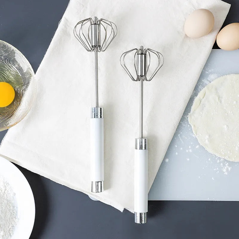 Semi-automatic stainless steel egg beater whisk with hand pressure rotating handle, silvery colour, on white background