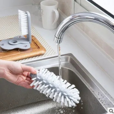 Grey suction cup brush with double-head design and two suction cups on a kitchen wall