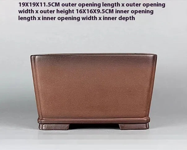 Brown handmade purple clay square flower pot with classical design on a wooden surface.