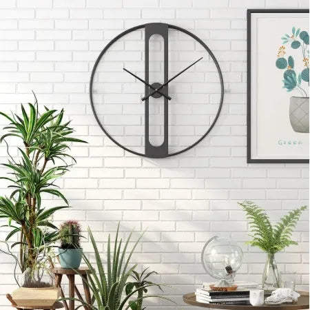 Round metal wall clock with 50 cm diameter in black or gold finish on a plain wall