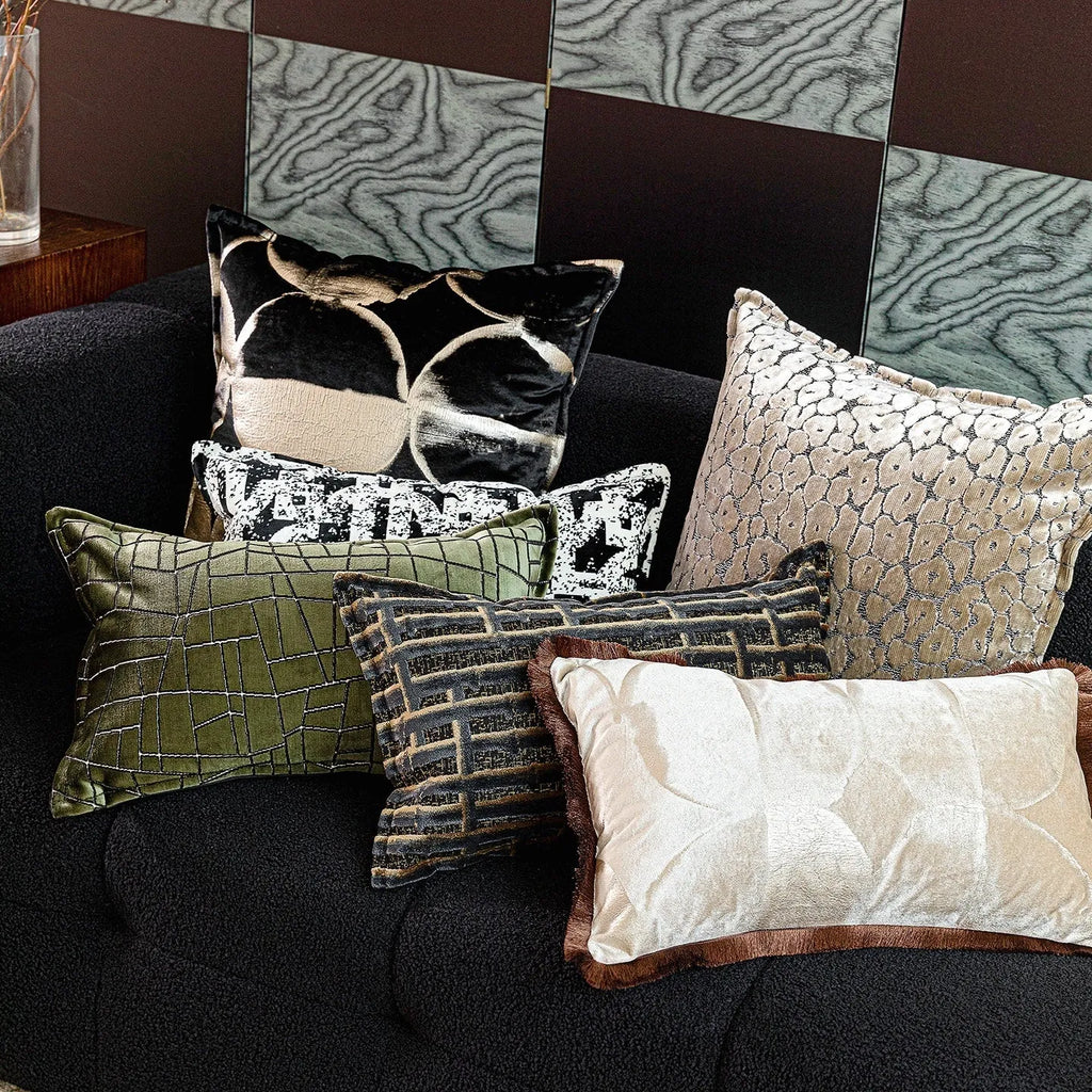 Black and gold abstract patterned decorative flannel cushion on a grey sofa.