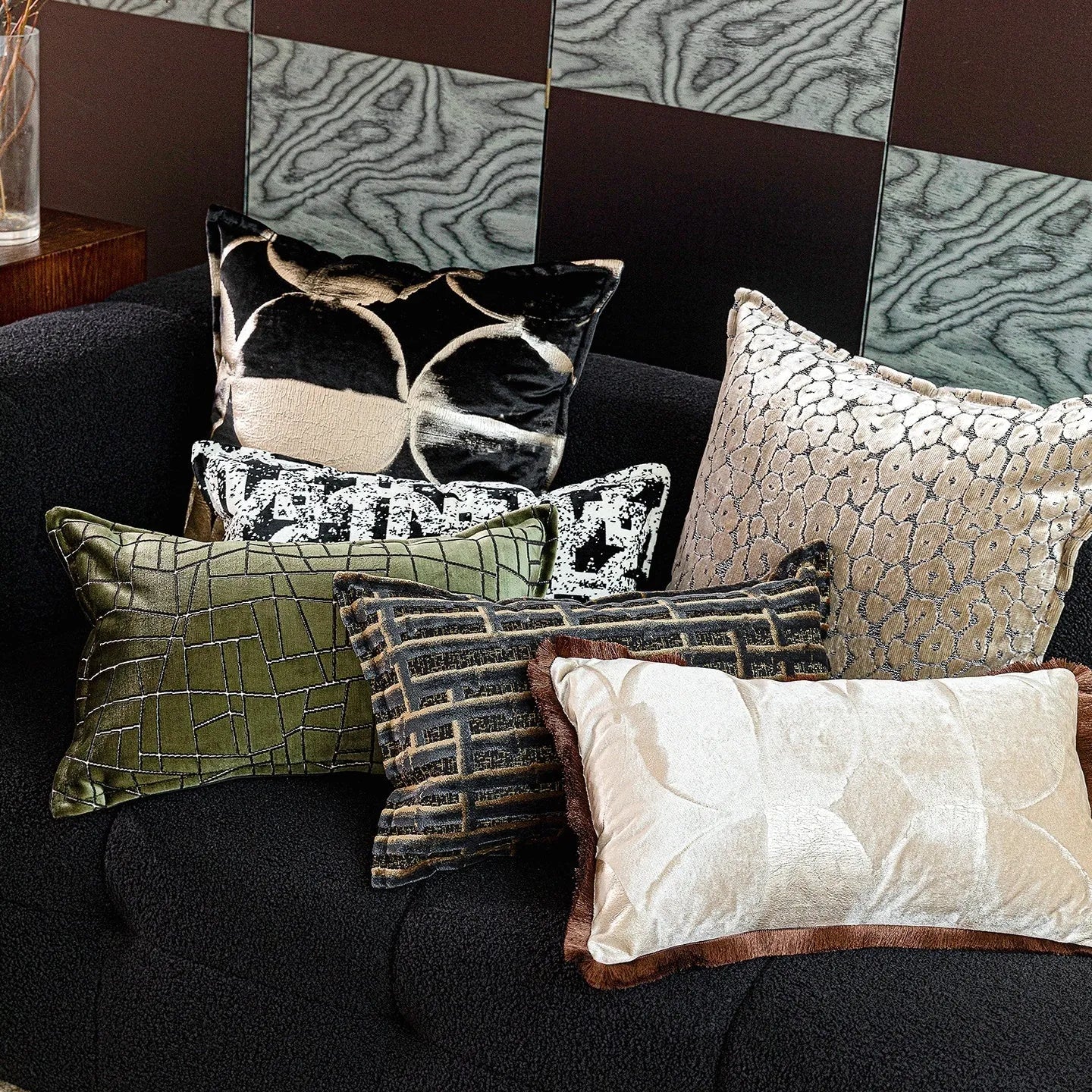 Black and gold abstract patterned decorative flannel cushion on a grey sofa.