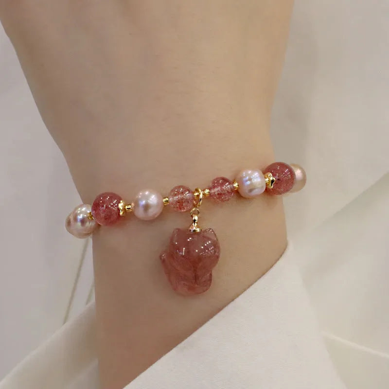 Women's natural freshwater pearl bracelet with light pink pearl, strawberry quartz, and fox charm on white background