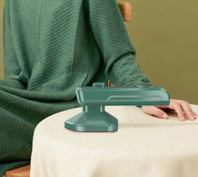 Dark green portable handheld hanging steam ironing machine with ceramic panel on a white background.