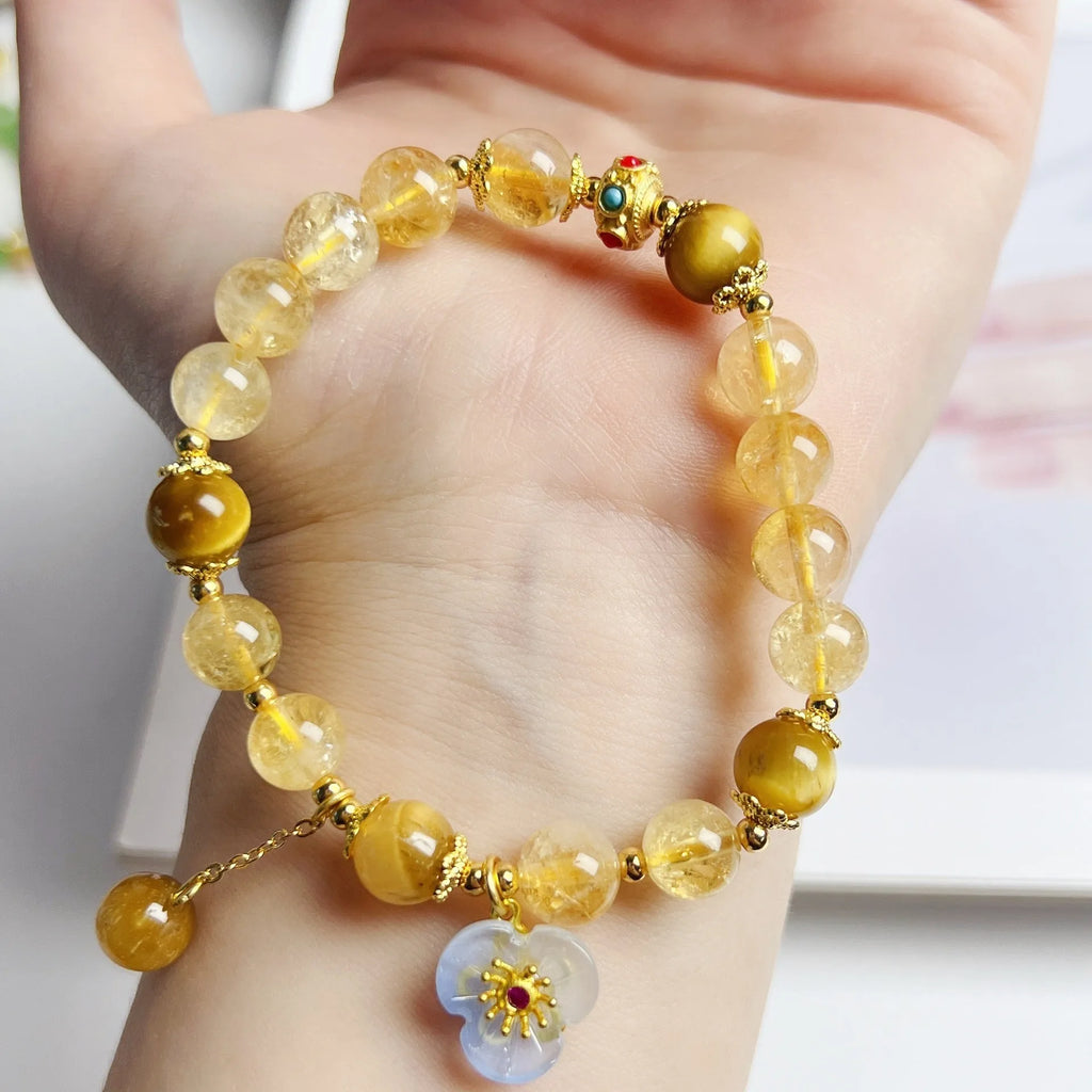 Women's handcrafted citrine crystal bracelet with flower tassel pendant on white background