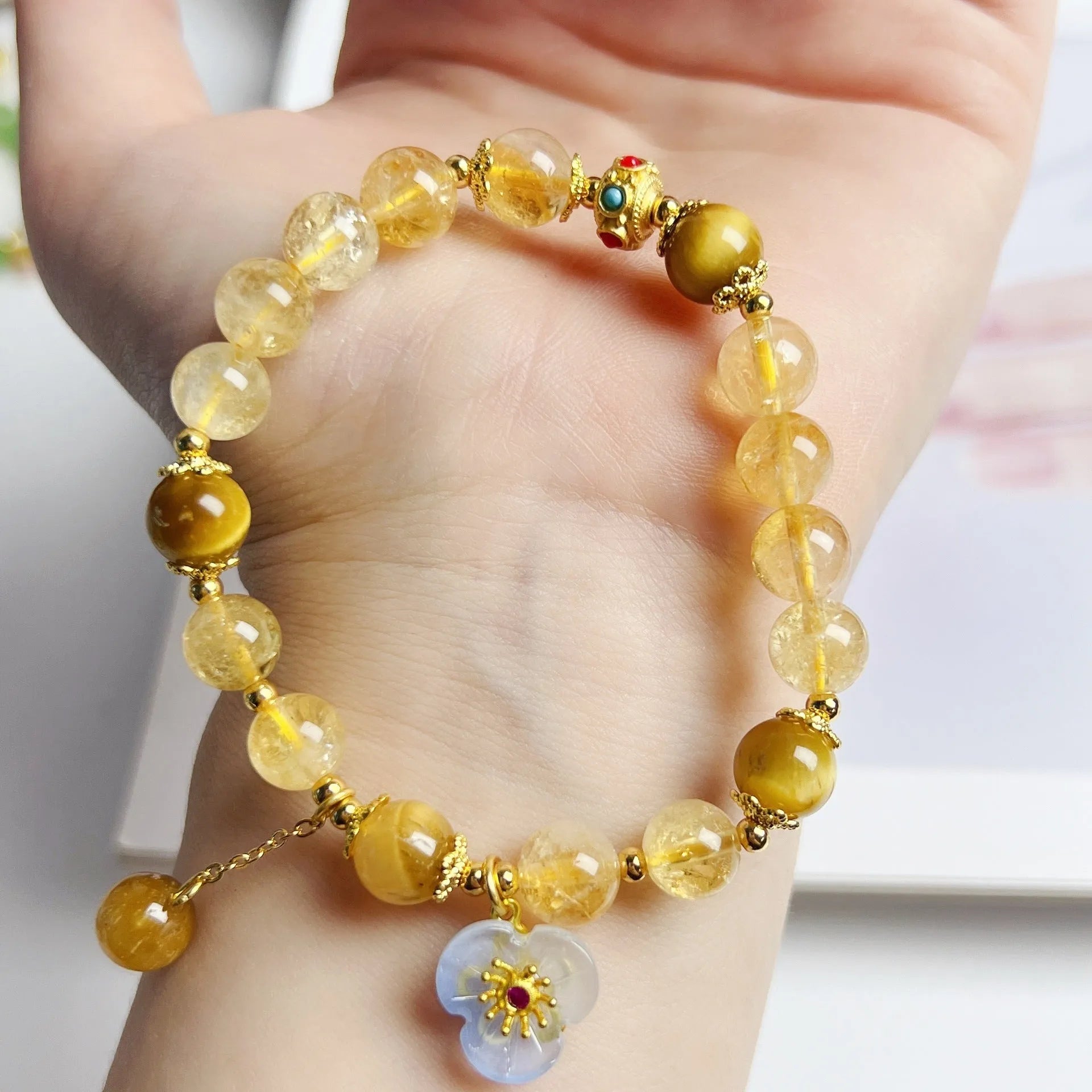 Women's handcrafted citrine crystal bracelet with flower tassel pendant on white background