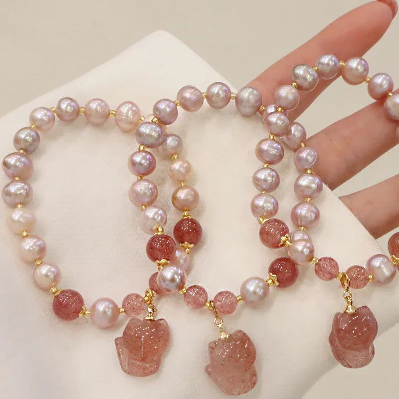 Women's natural freshwater pearl bracelet with light pink pearl, strawberry quartz, and fox charm on white background