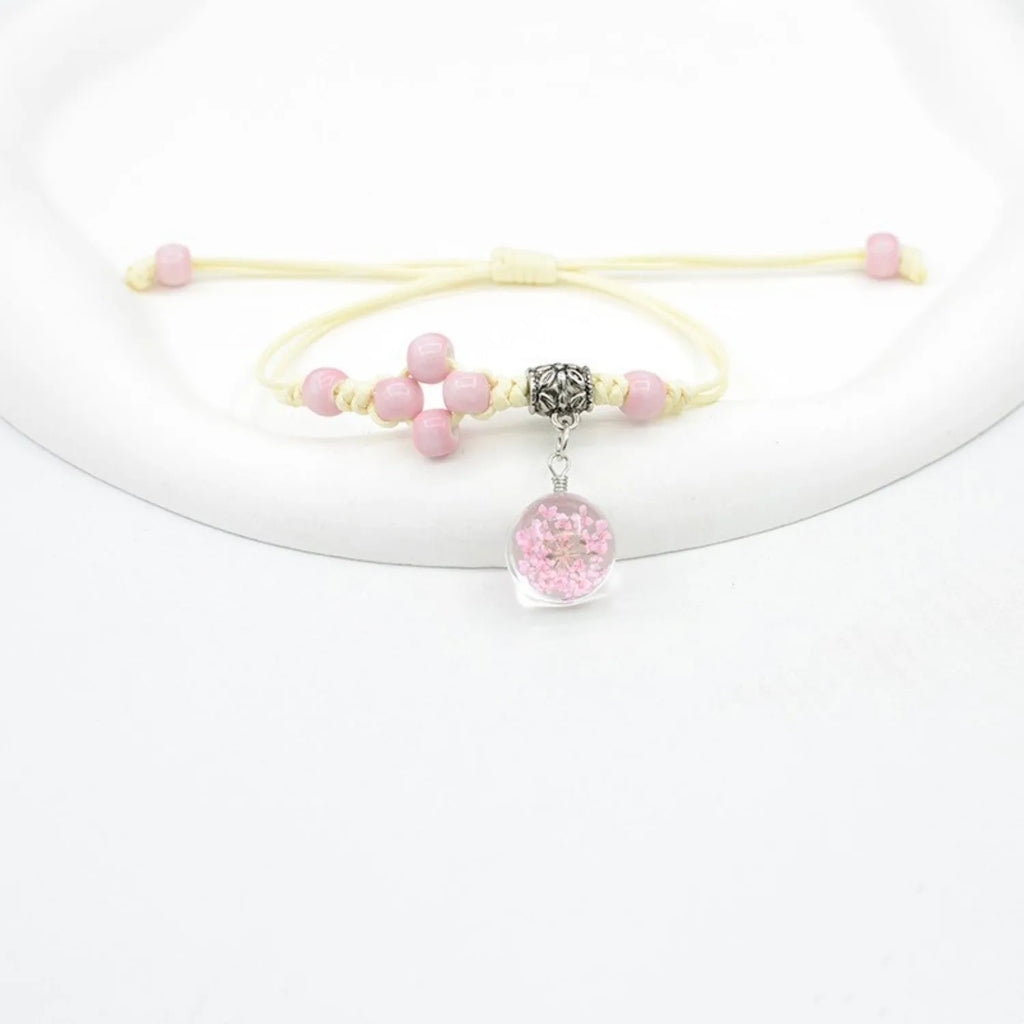 Close-up of a women's glass bracelet with large 1.4cm beads containing dried flowers and a hand-woven lace pattern.