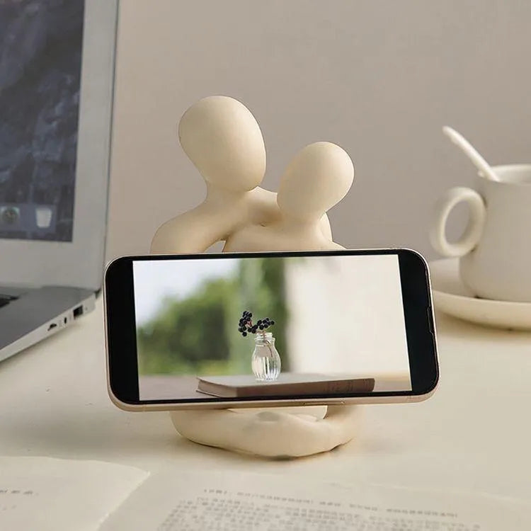Modern milky white resin statue of an embracing couple, 12cm tall, on a wooden desk.