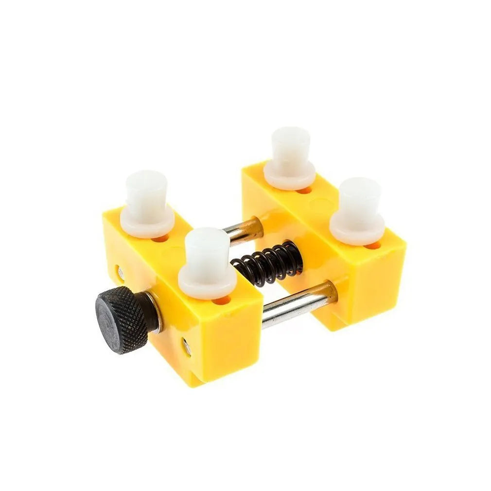 Yellow plastic watch repair case opener kit with mounting base and four fixing pillars on a workbench