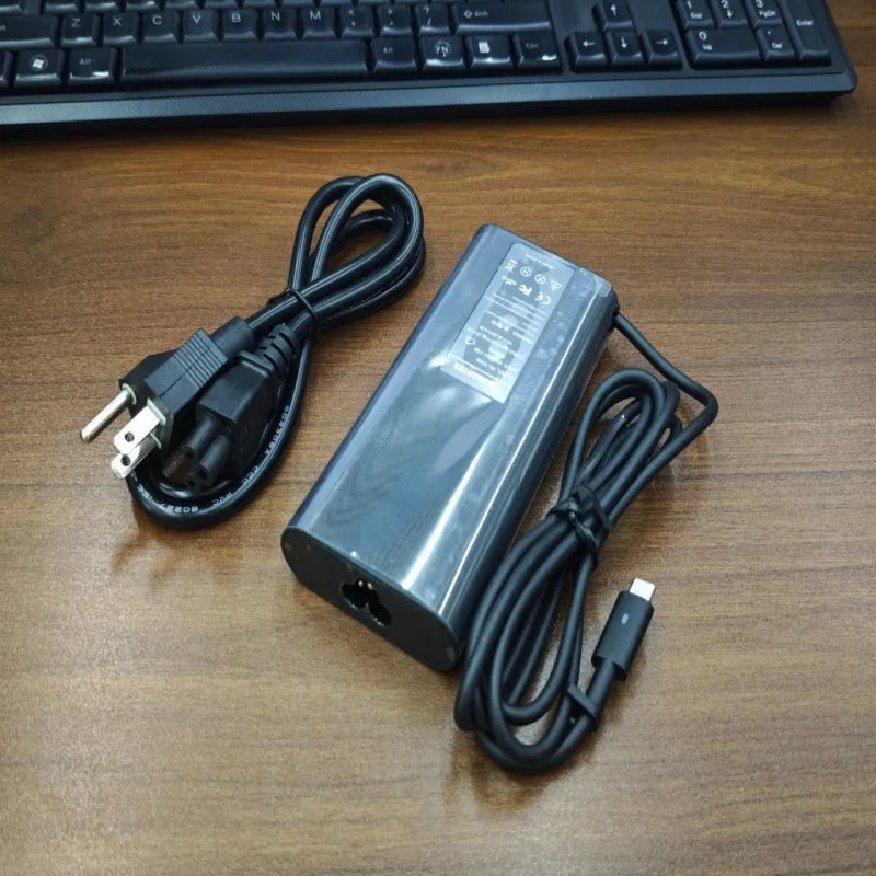 Black 65W USB-C laptop power adapter with multiple international plug attachments