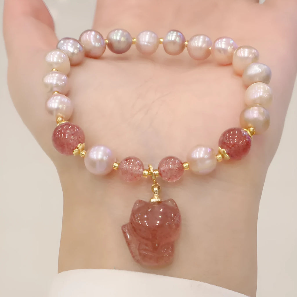 Women's natural freshwater pearl bracelet with light pink pearl, strawberry quartz, and fox charm on white background