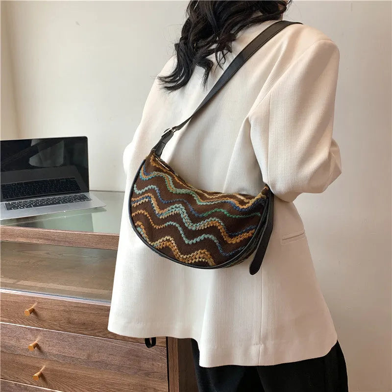 Women's knitted straw woven crossbody bag showing woven texture and internal phone and document pockets