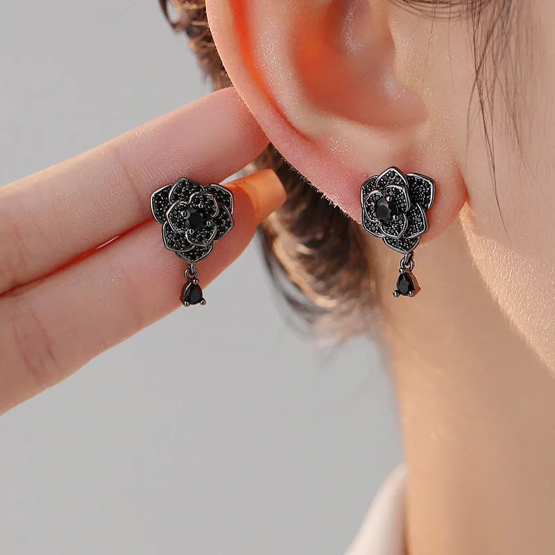Black rose zircon inlaid stud earrings with 18K gold plated copper flower shape on white background