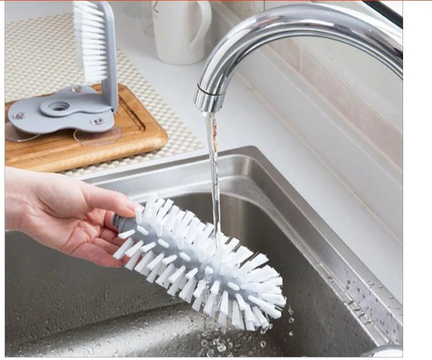 Grey suction cup brush with double-head design and two suction cups on a kitchen wall