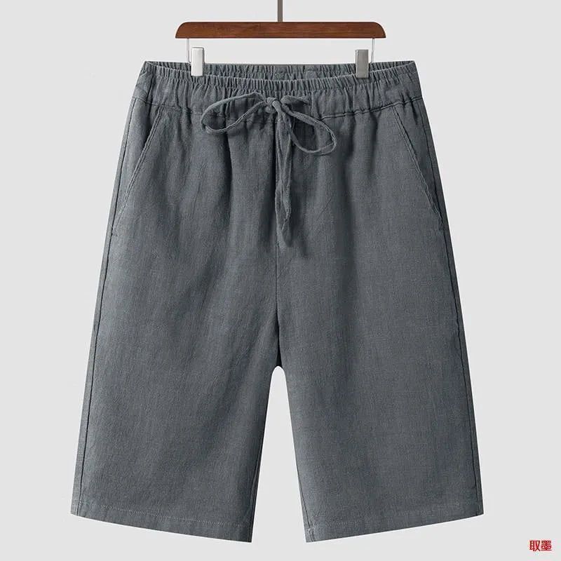 Man wearing beige linen shorts with a loose cropped fit and elasticated mid waist.