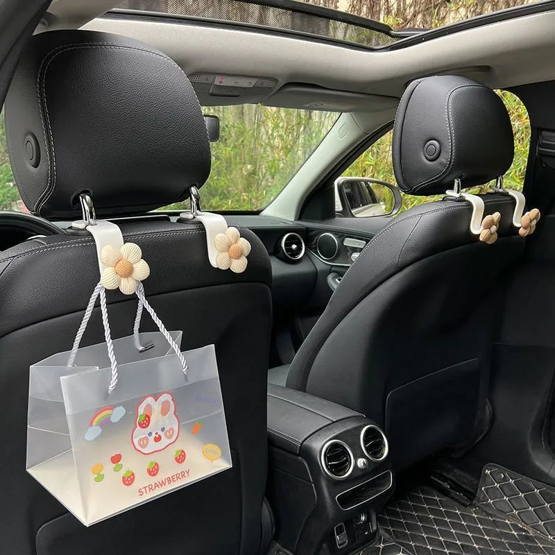 Plastic car seat hook in white, 11 by 5.5 cm, hanging from a headrest
