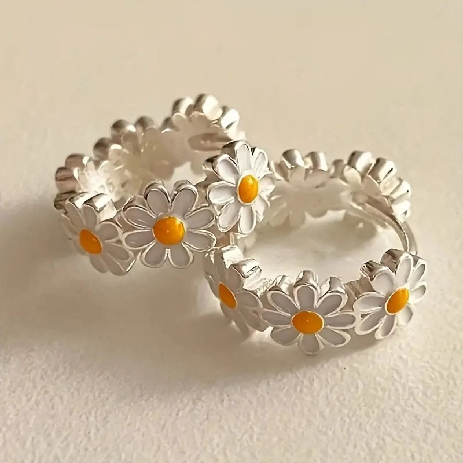 A pair of white daisy flower design ring earrings with a platinum-inlaid gemstone accent.