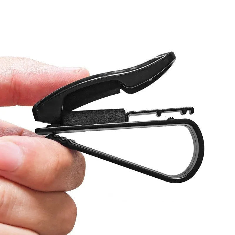 Black plastic clip for car sunshade holding a ticket and glasses