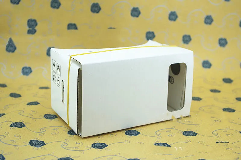 Pink and white cardboard VR headset for smartphones with adjustable straps and 3D lenses.