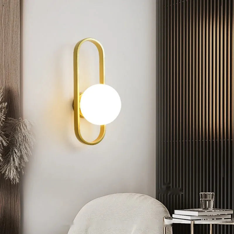 Minimalist modern wall lamp with iron body and glass shade in black or gold finish.
