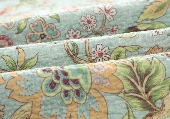 Blue American floral and bird pattern on a pure cotton quilt set with pillowcases, laid on a bed.