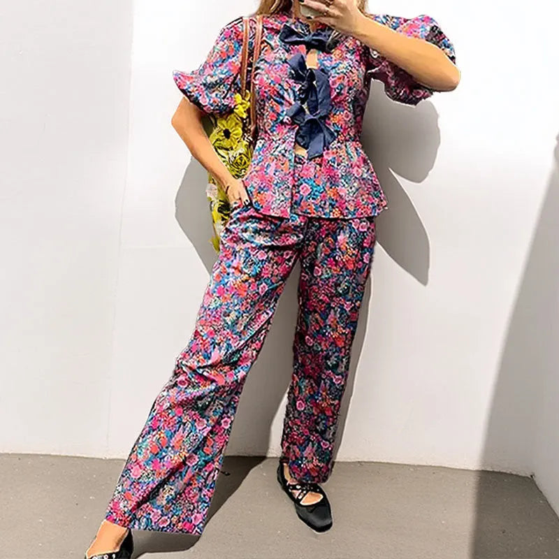 Women's floral printed trousers suit with tie-neck top featuring puff sleeves and matching trousers