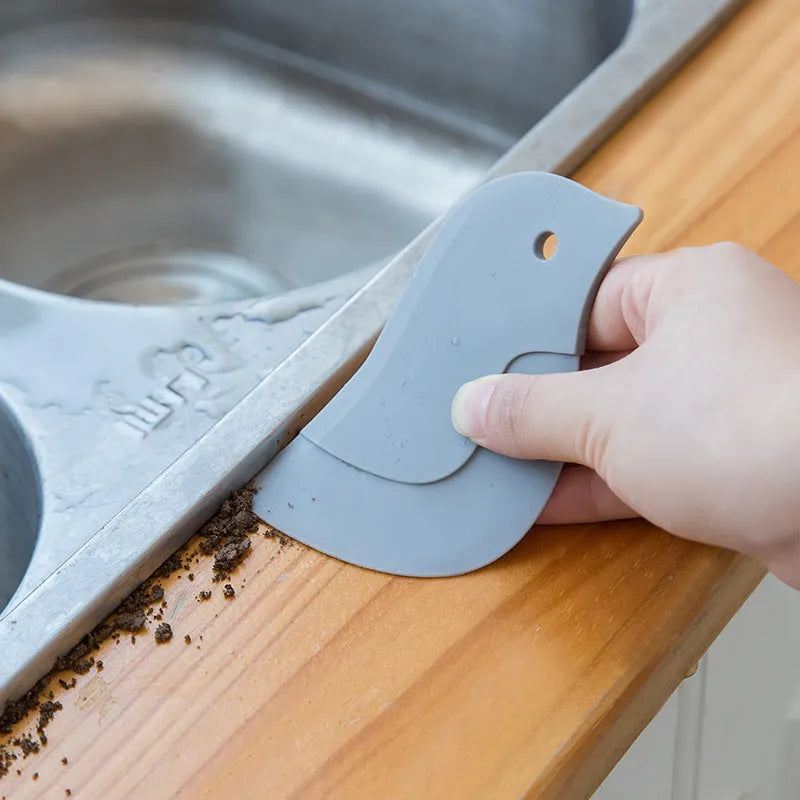 Penguin shape soft blade scraper 11x7cm in green cleaning a plate with sauce residue