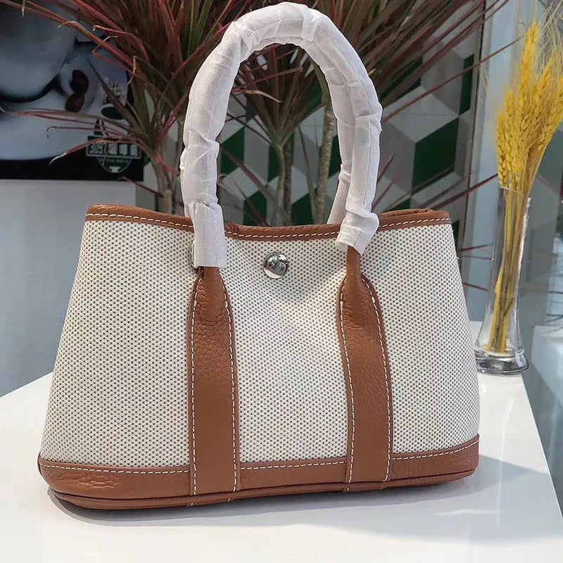 Women's canvas bucket tote bag with leather trim showing crossbody strap and internal compartments