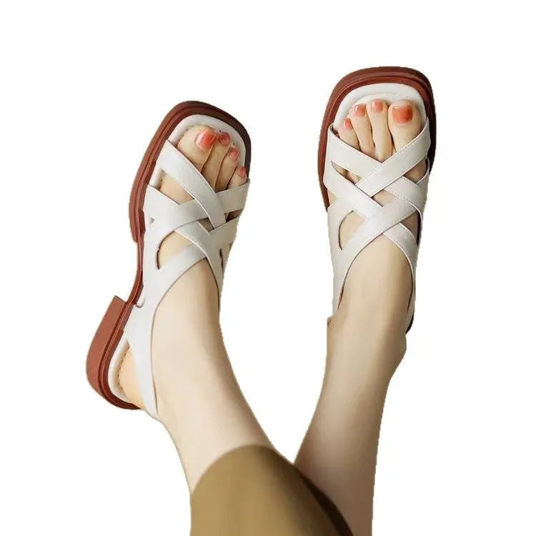 Glossy black patent leather women's sandals with square toe and winding tape closure on a rubber sole.