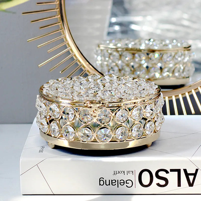 Clear crystal glass jewellery box with a French gold metal frame on a table.