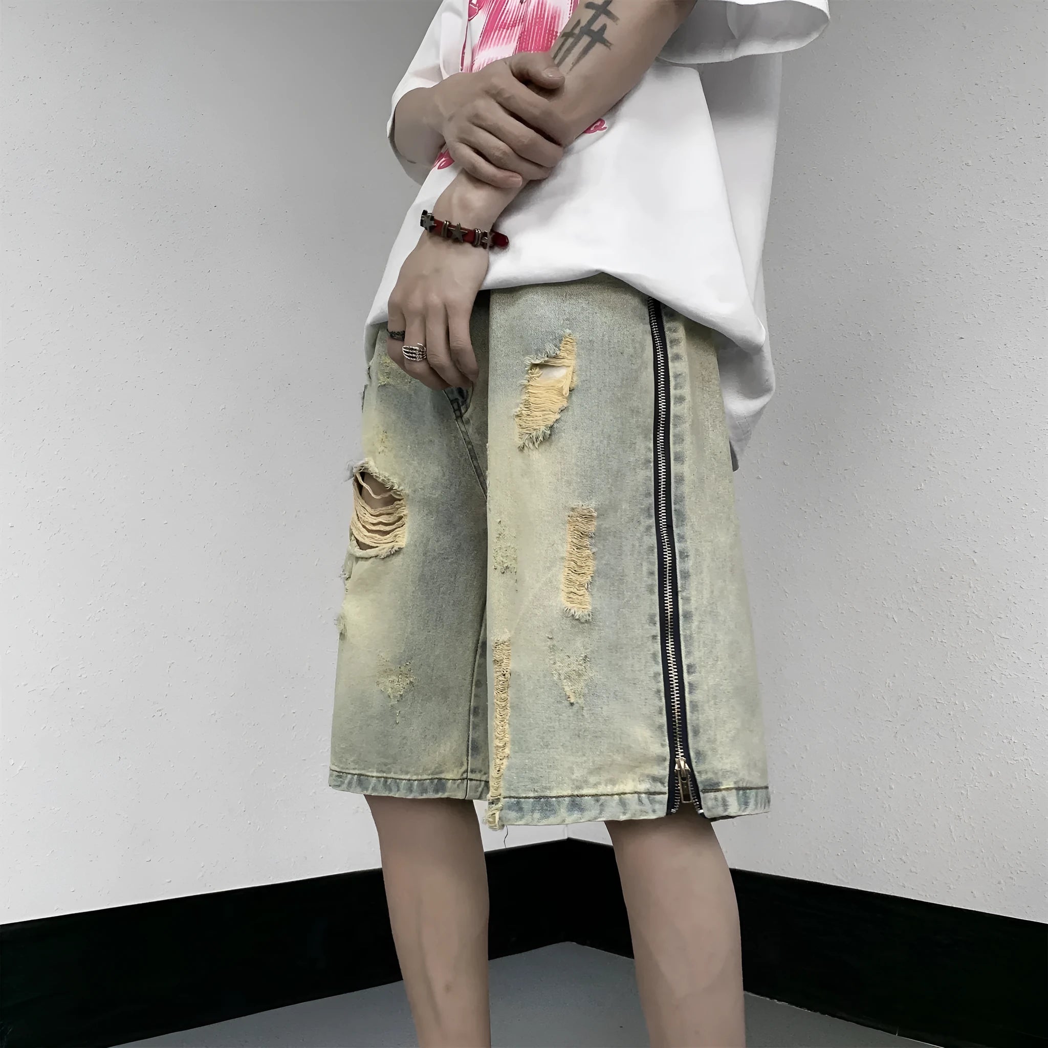 Men's loose five-point denim shorts in blue with ripped yellow-mud effect, straight leg, button fly, front view