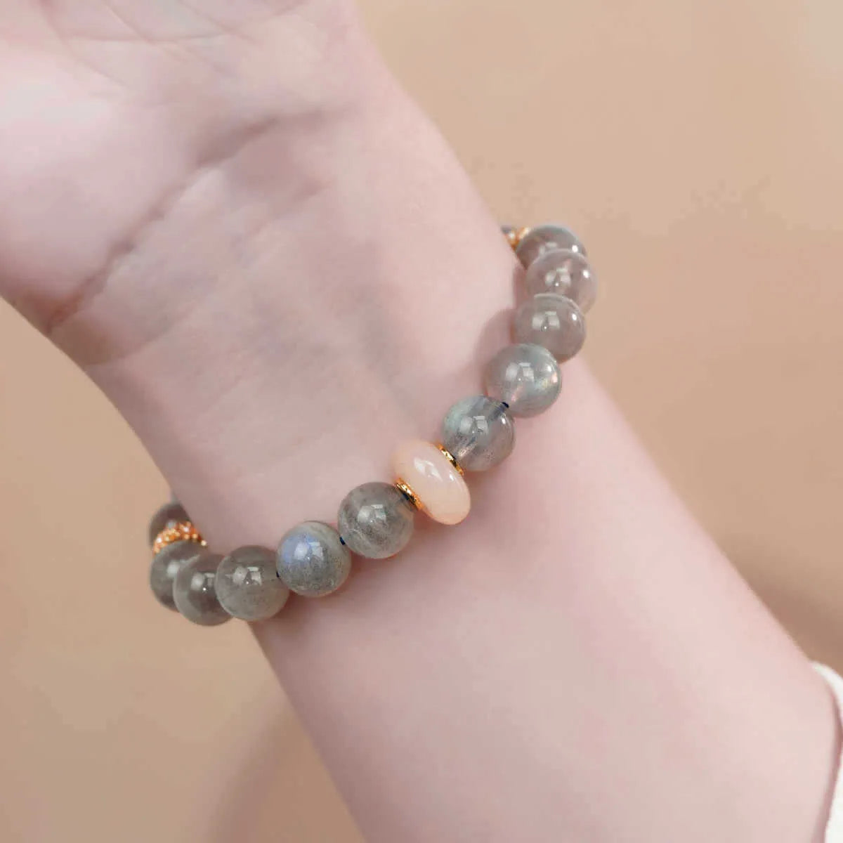 Gray moonstone agate half bracelet with round 8mm beads on a plain background