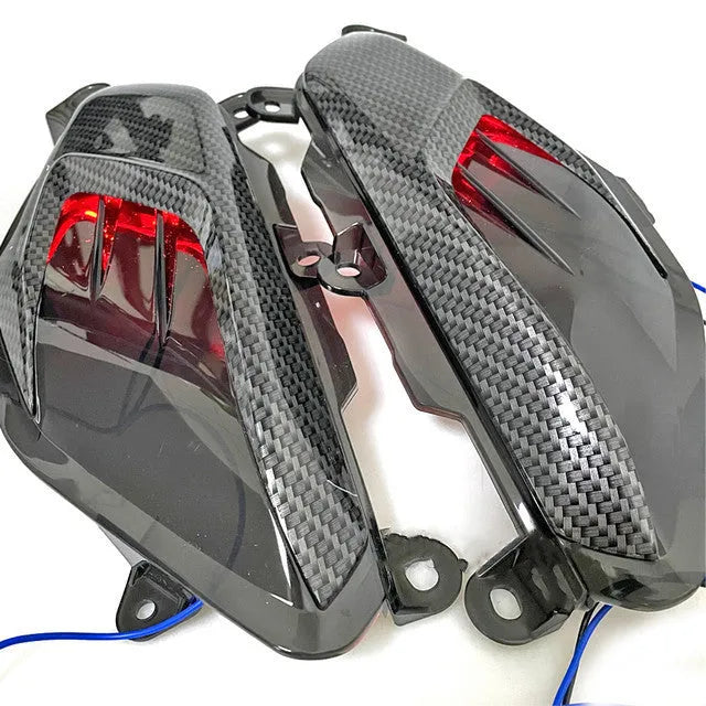 Pair of Yamaha NMAX LED side lamps with carbon fibre decoration, showing blue and red illumination options.