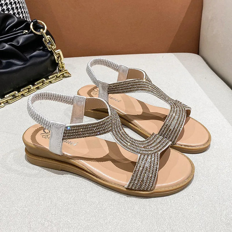 Women's gold patent leather beach sandals with rhinestone decoration on a rounded toe strap.