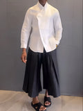 White asymmetric front long sleeve shirt and black pleated pants set on display