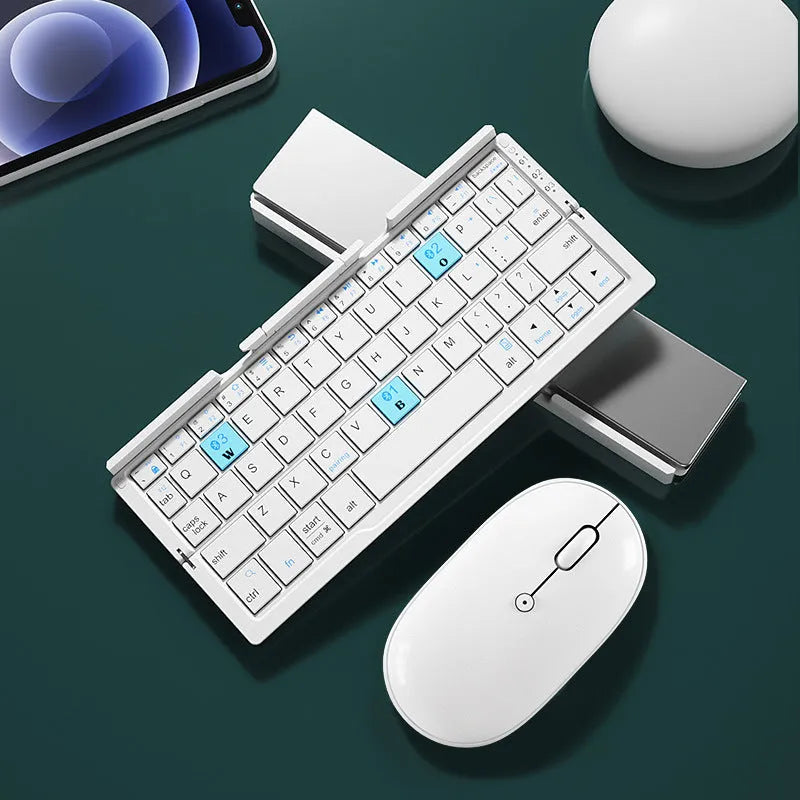 Silver white mini folding Bluetooth keyboard open next to a smartphone on its integrated stand.