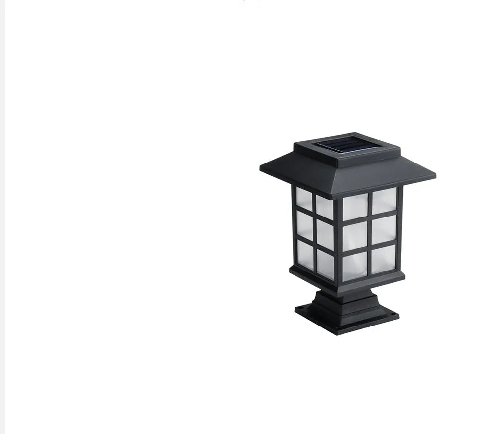 Solar outdoor LED lawn light with black body and white light through windows, set in a garden flower bed