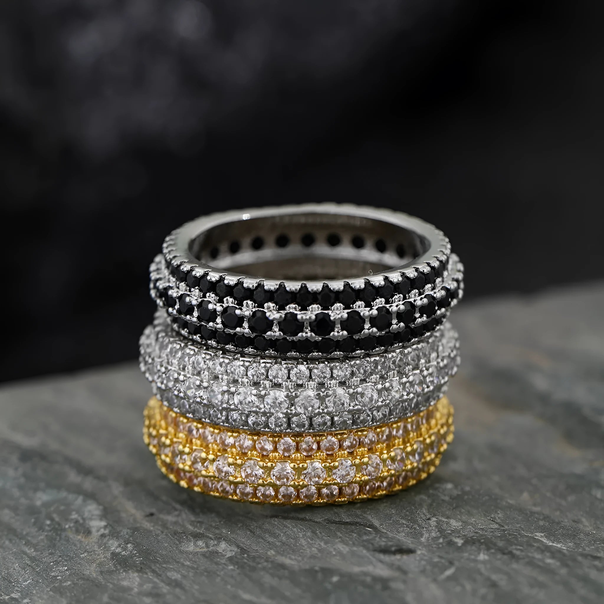 Geometric triangle personalised zircon ring in yellow gold on a grey background.