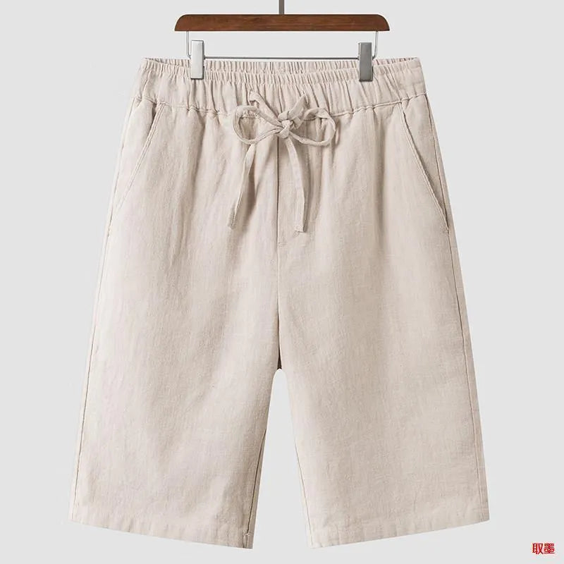 Man wearing beige linen shorts with a loose cropped fit and elasticated mid waist.
