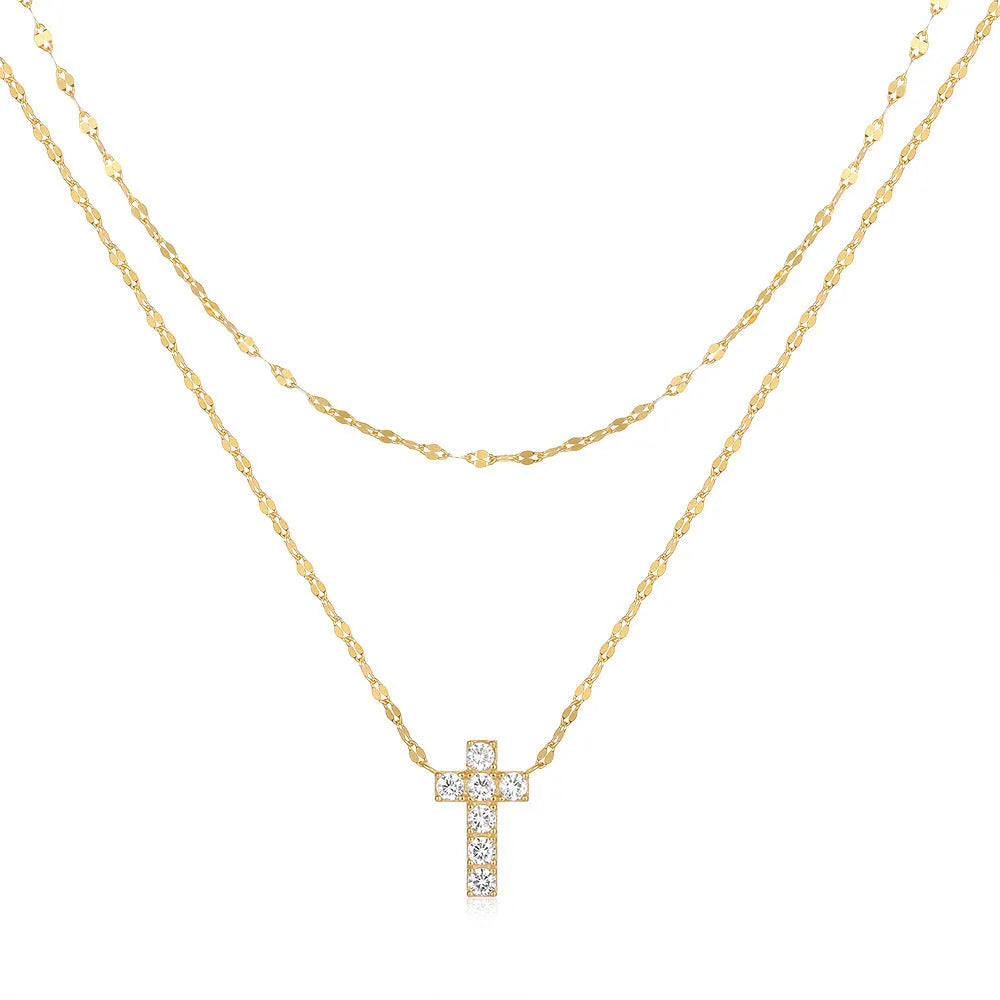 Close-up of a sterling silver double-layer cross pendant necklace with twin diamond accents on a clavicle chain.